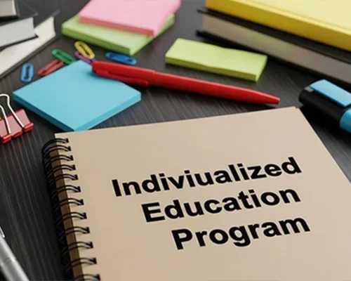 Notebook titled 'Individualized Education Program' with stationery items around.